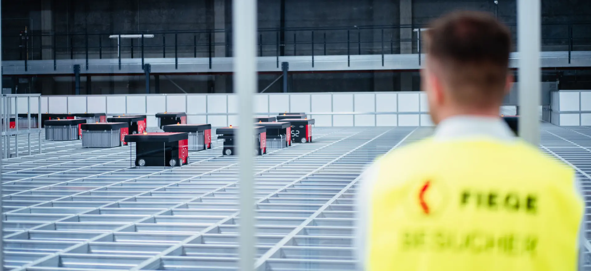 FIEGE-Mitarbeiter vor einem AutoStore-Lagersystem mit Transportrobotern